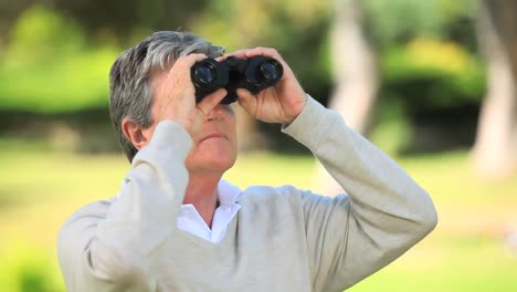 mature man watching something through binoculars