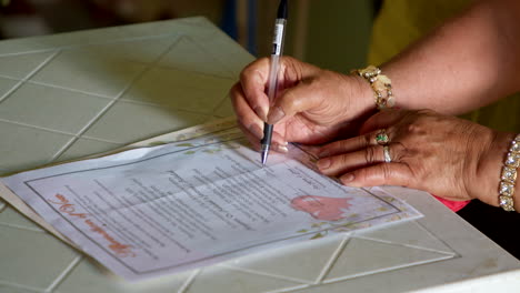 elder woman signing marriage renewal vows certificate