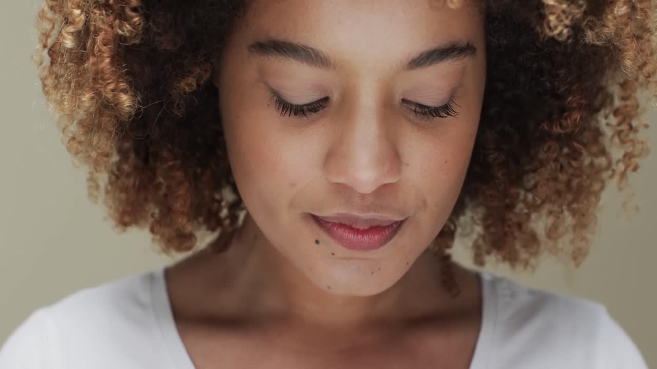 Biracial woman with dark hair on beige background, slow motion