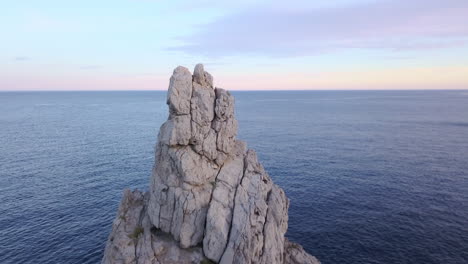 drone pan up shot of ibiza's iconic rock benirrás