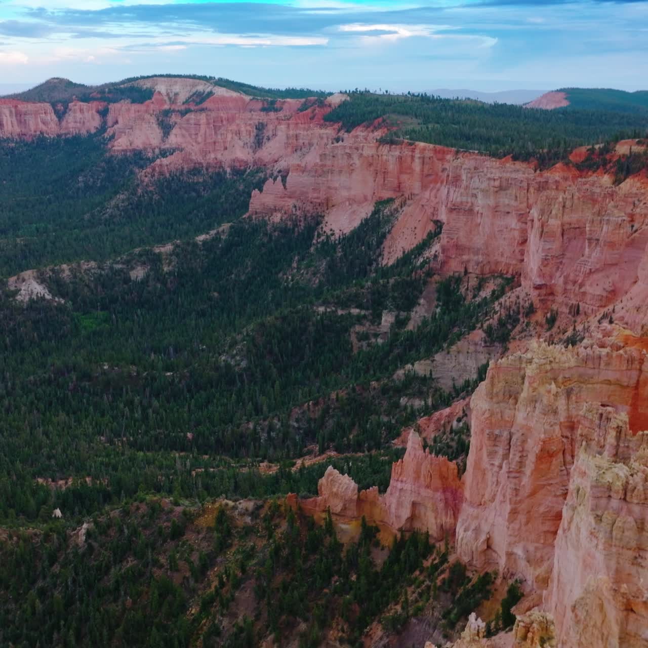 Sheer cliffs of wonderful canyons rising over the pine tree woods. Blue skies with clouds at backdrop. Aerial view