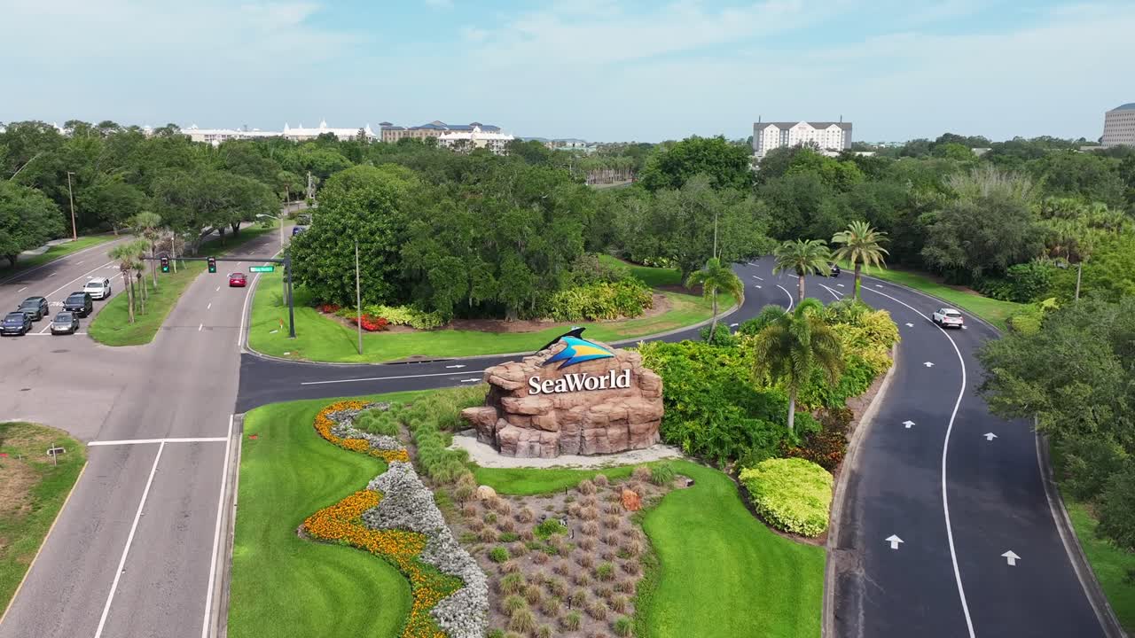 SeaWorld entrance sign surrounded by manicured landscaping and palm trees. Roads lead to the park. Aerial view of SeaWorld Orlando’s entrance.
