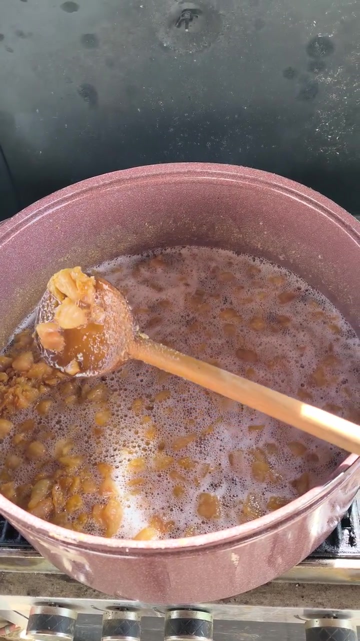 Ripresa verticale di ciccioli mescolati su una griglia esterna durante la preparazione di cibo tradizionale.