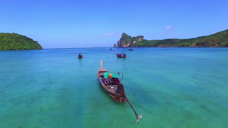 low aerial view of the turquoise bay and longtail boats