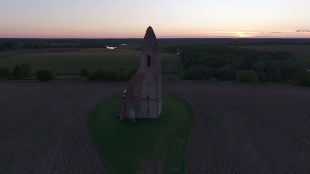 Gamle kirkeruiner rejser sig over et solnedgangsbelyst landskab, Ungarn