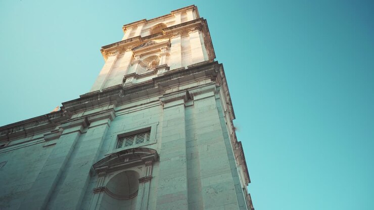 Lisboa Alfama, antiga torre de igreja e convento com fachada ornamentada ao nascer do sol, gravação em movimento 4K.