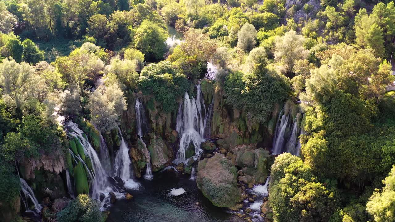 Person practicing water sport at Jajce waterfalls. Aerial forward