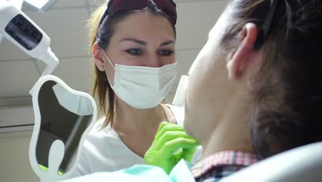 estomatóloga en máscara. médica trabajando. paciente mirándose en el espejo. vista de cerca. filmado en 4k