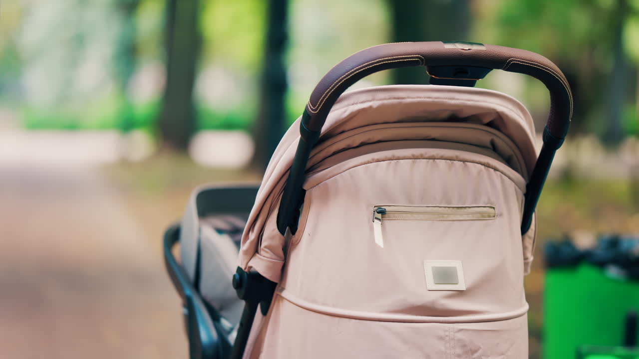 A beige baby stroller parked on a forest path in a park