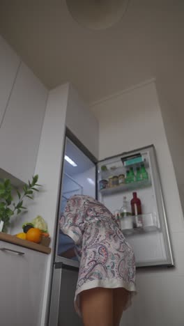 woman getting food from refrigerator in the morning