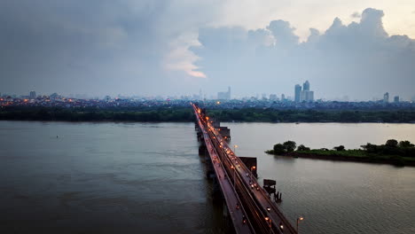 long bien bridge traffic with hanoi city skylines in background at sunset, panoramic drone shot