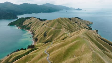 aerial view of campervan on a road trip traveling along remote, winding scenic road in the wilderness of te aumiti french pass in marlborough sounds, south island of new zealand aotearoa