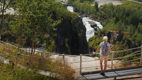 a woman looks at the majestic waterfall of woringsfossen in norway impressive beauty of scandinavian