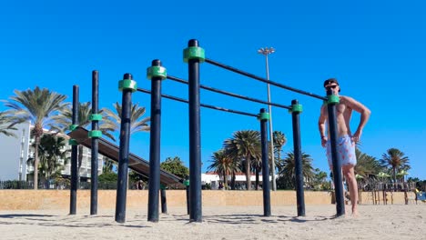 man doing a bar dip workout at a sunny beach, fit caucasian male training calisthenics, shot in fuerteventura