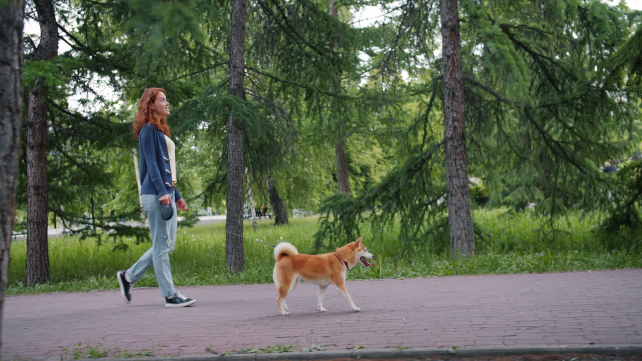 mujer paseando al perro en el parque