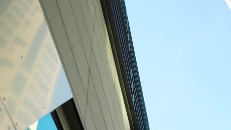 looking up at a modern building's edge against a clear sky