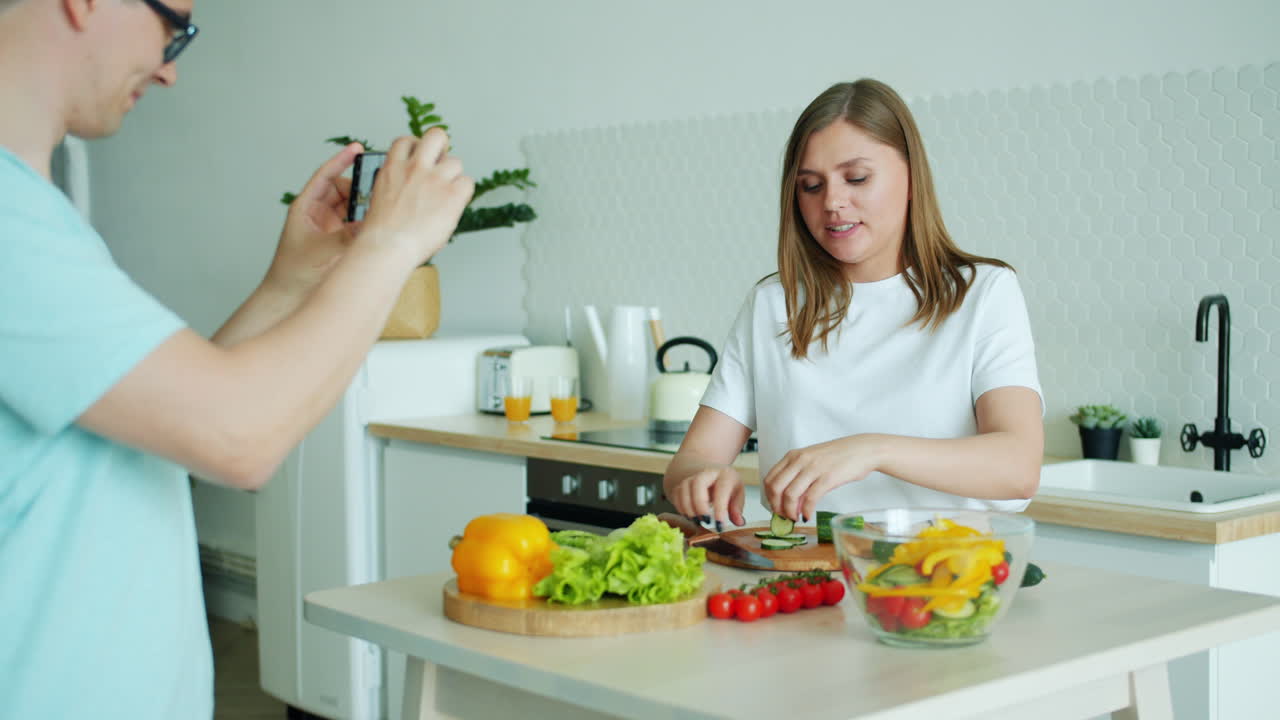 Couple preparing a healthy salad and taking photos