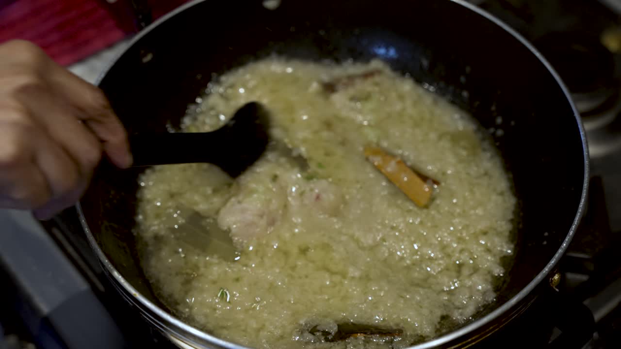 Spoon Stirring Simmering Onions In Pan With Cinnamon Sticks, evoking the essence of cooking mastery and meticulous food preparation