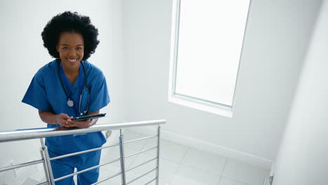 Portrait-Of-Female-Doctor-Or-Nurse-With-Digital-Tablet-Checking-Patient-Notes-On-Stairs-In-Hospital