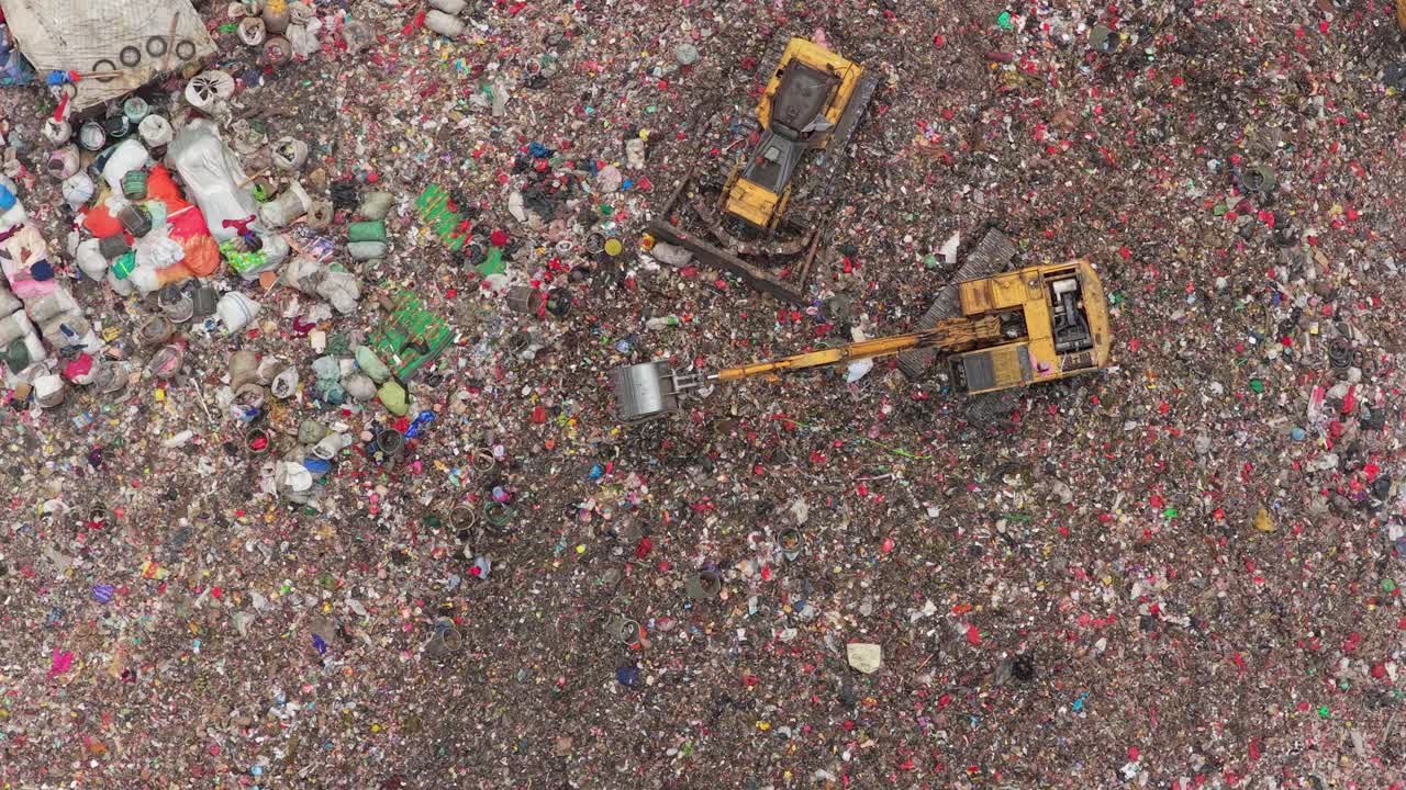 Bulldozer ed escavatore che gestiscono i rifiuti nella discarica di Bantar Gebang.