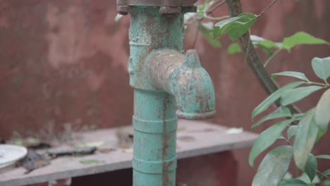 Tiro-Circular-De-Un-Viejo-Grifo-Oxidado-Afuera-Cerca-De-Hojas-Verdes