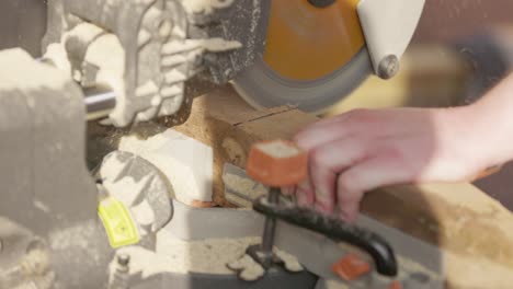 hand-held shot of a wooden post being cut effortlessly with a mitre saw