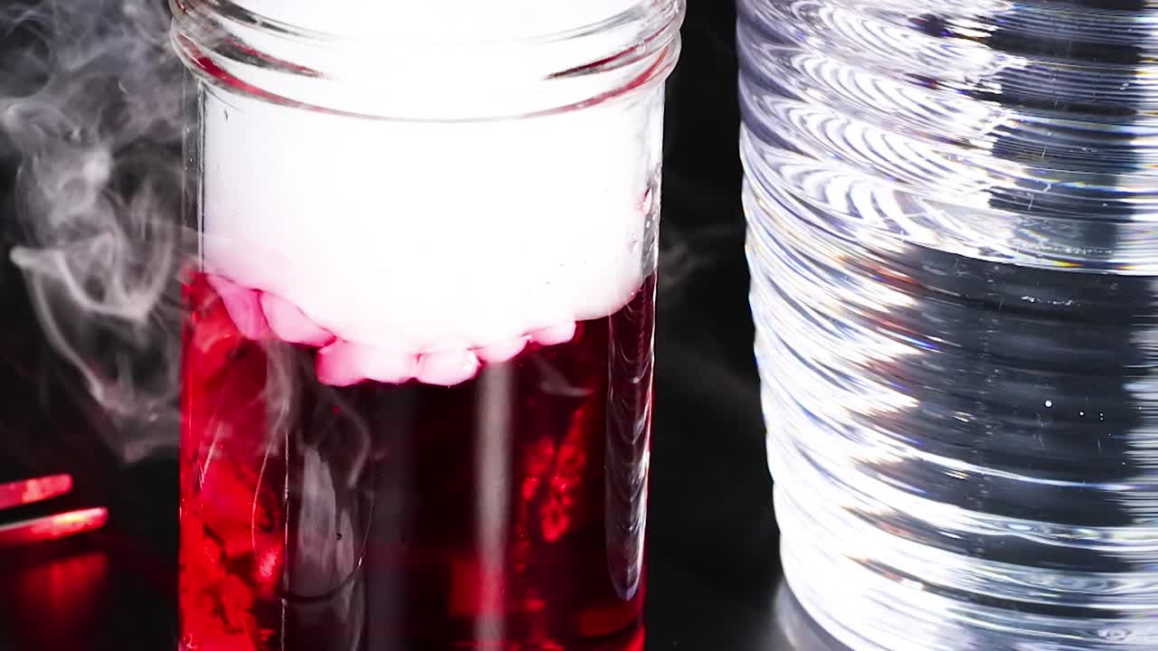 A red liquid in a jar emits white smoke, creating a striking visual effect.
