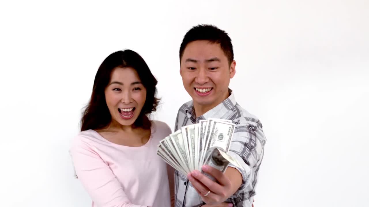 행복한 아시아 커플이 돈을 보여주고 있습니다.