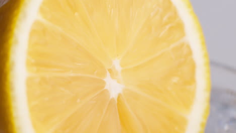 cold fresh sparkling water pouring into a glass with ice and lemon slices