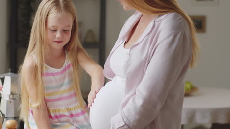 little girl touches and listens to pregnant mother's belly