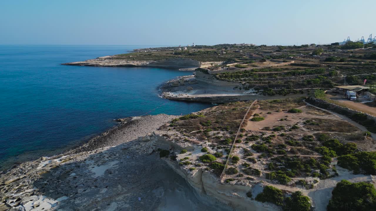 Vista aerea panoramica ad ampio angolo con drone di St. Peter’s Pool, Malta. Una piccola spiaggia rocciosa, acque turchesi e piscine costiere naturali creano uno splendido mare Mediterraneo