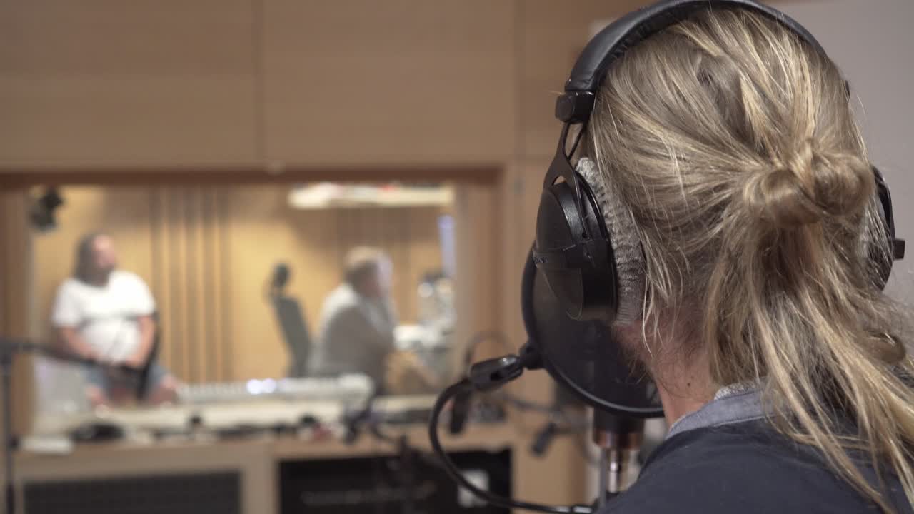 Man singing in recording studio in background, doing hand gestures and pointing front, back close up view