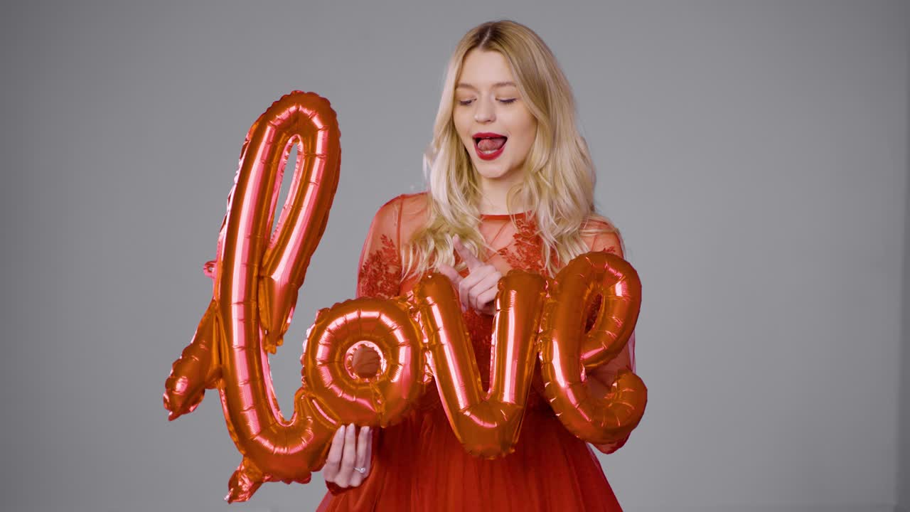 사랑의 풍선을 들고 있는 빨간 드레스를 입은 여자