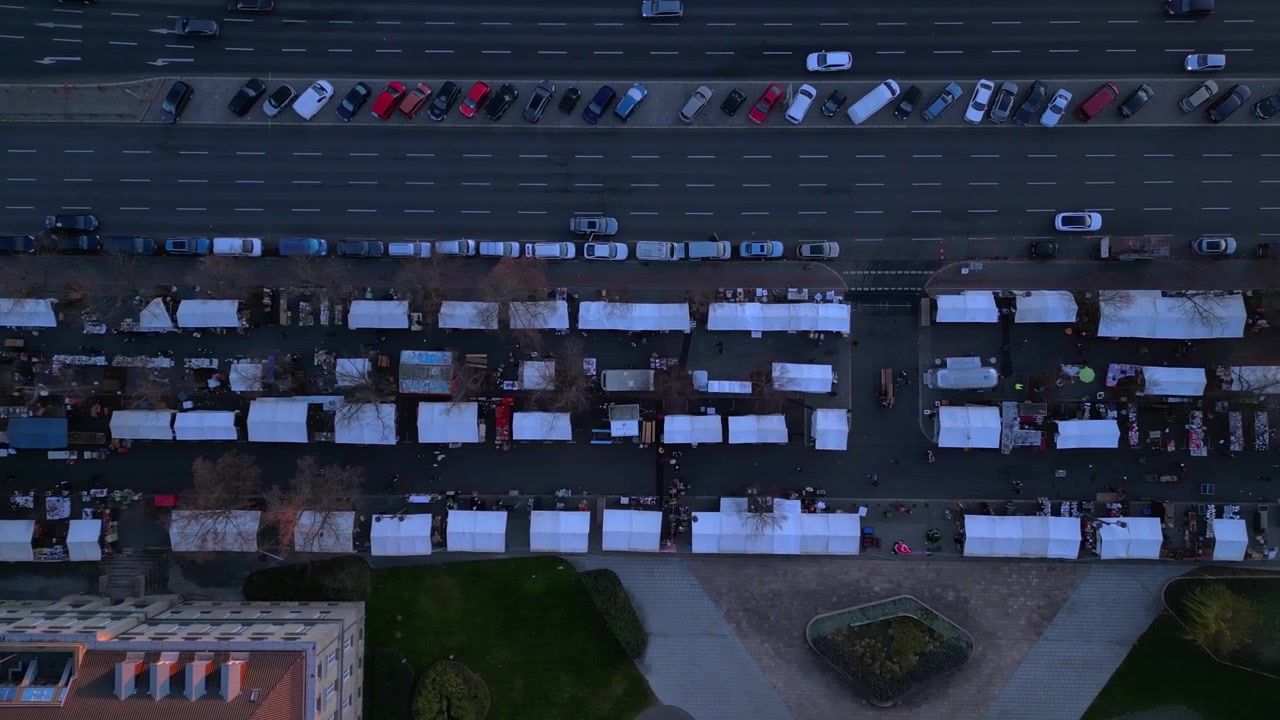 flea market taking place in front of Federal Office for Building, located in berlin, germany Smooth aerial view flight drone shot footage from above