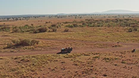 Toma-Aérea-De-Un-Fotógrafo-De-Vida-Silvestre-Conduciendo-Un-Vehículo-De-Safari-En-La-Sabana-De-La-Reserva-Nacional-De-Maasai-Mara,-Kenia,-áfrica-Con-Hermosos-Paisajes,-Conservación-Del-Norte-De-Masai-Mara