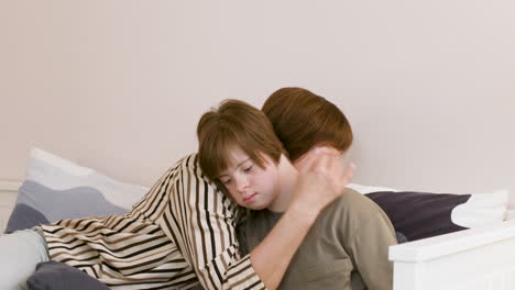 woman kissing her daughter while she reads a book