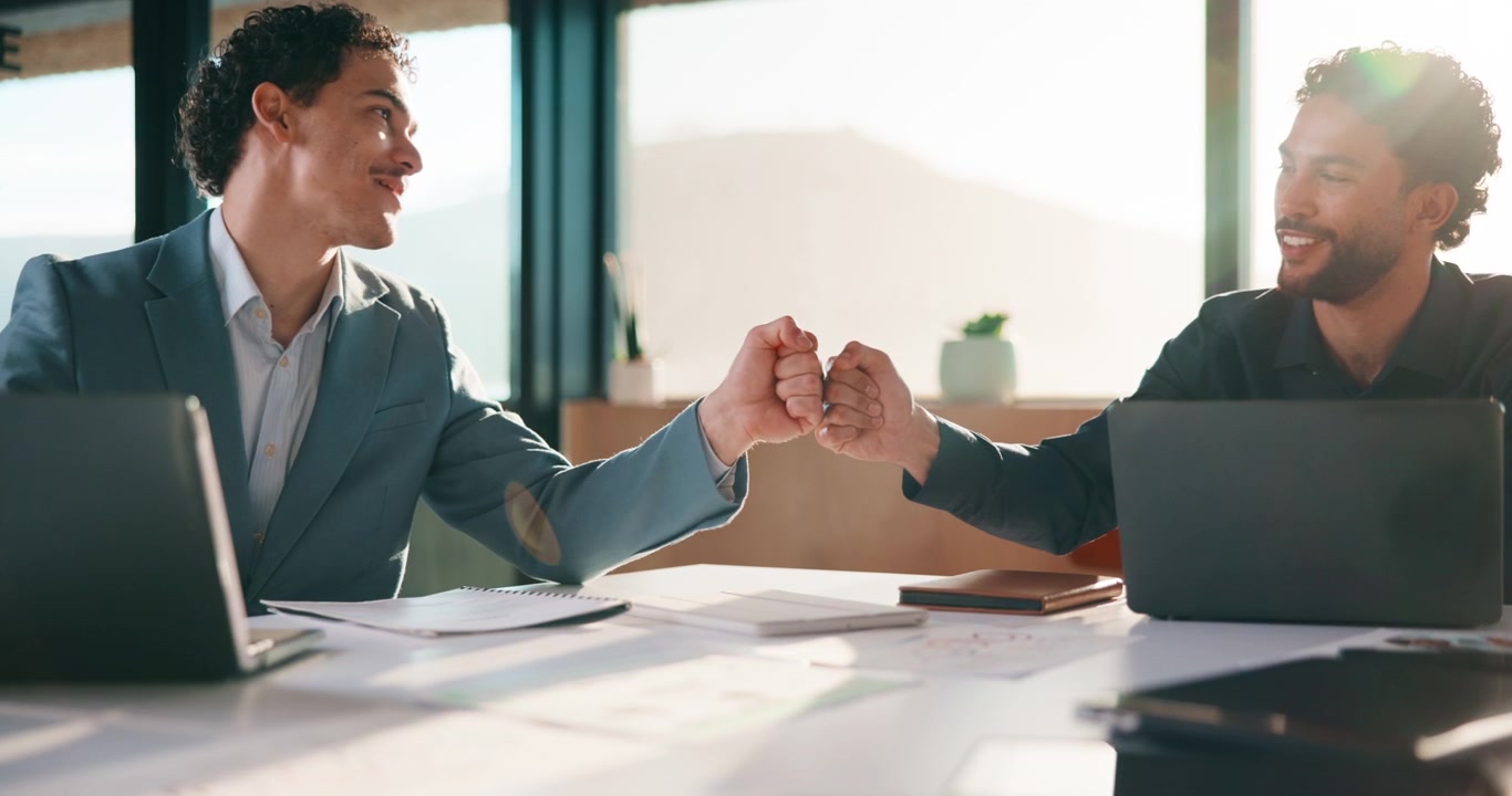 Two Businessmen Collaborating on Laptops and Celebrating with a Fist Bump