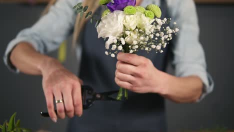 Close-Up-view-of-hands-of-professional-female-floral-artist-preparing-a-bouquet,-florist-cutting-flower-stems-at-flower-shot
