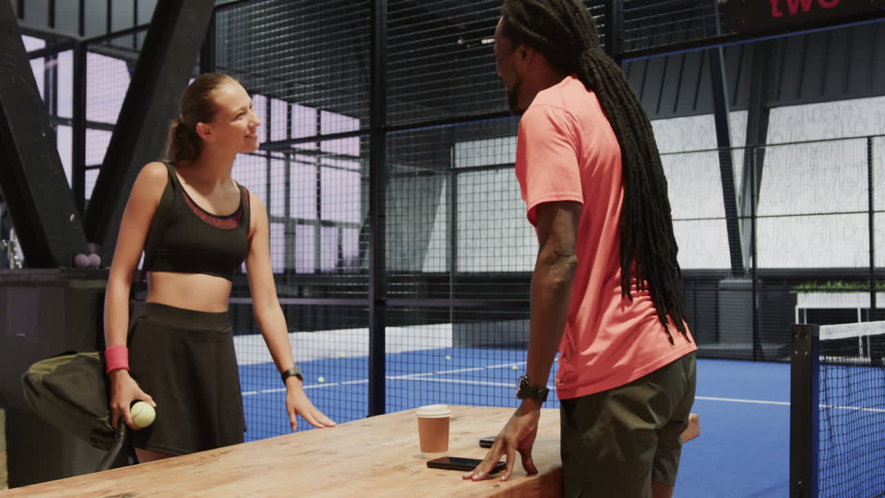 Young diverse athletes preparing for padel tennis match, discussing strategy with focus, on indoor c