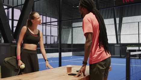 young diverse athletes preparing for padel tennis match, discussing strategy with focus, on indoor c
