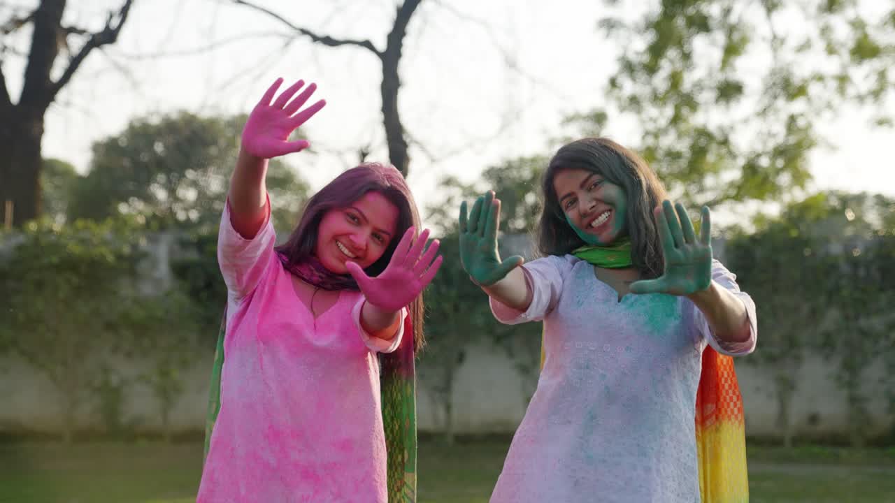 Ragazze indiane che sorridono e mostrano le mani colorate a una festa Holi