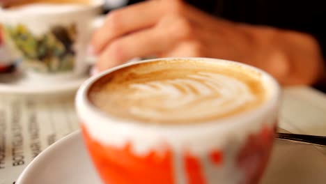 two people drink a wonderful cappuccino served in cups with artistic painting