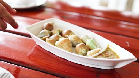 hand presenting seafood dish on red table