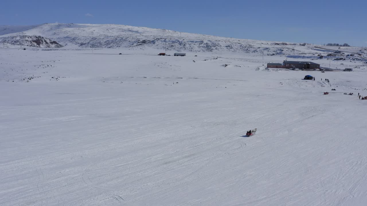 Drone of horse dragging carriage over frozen cildid lake in Turkey