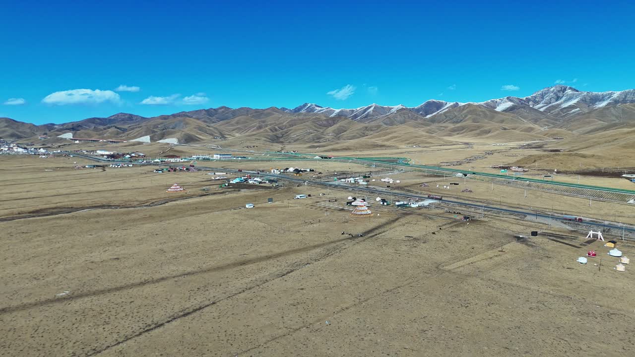 Qilian Grassland, Xining, Qinghai Province, China - A Vast Highland Plain Dotted with Small Settlements, Colorful Tents, and Roads Stretching Toward Rugged Mountains - Aerial Drone Shot