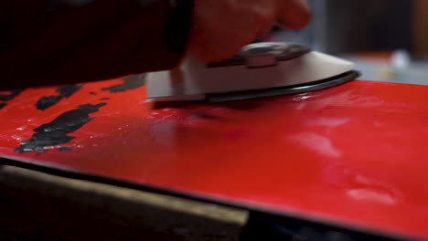 closeup shot ironing hot wax onto snowboard