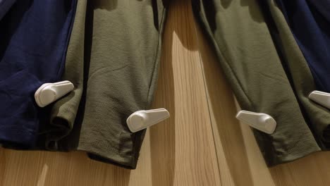 green and blue pants hanging on a rack in a store.