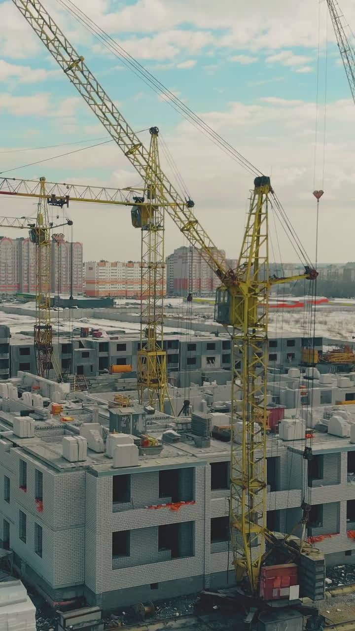 new building district construction site with yellow non-functioning cranes on spring cloudy weekend aerial motion