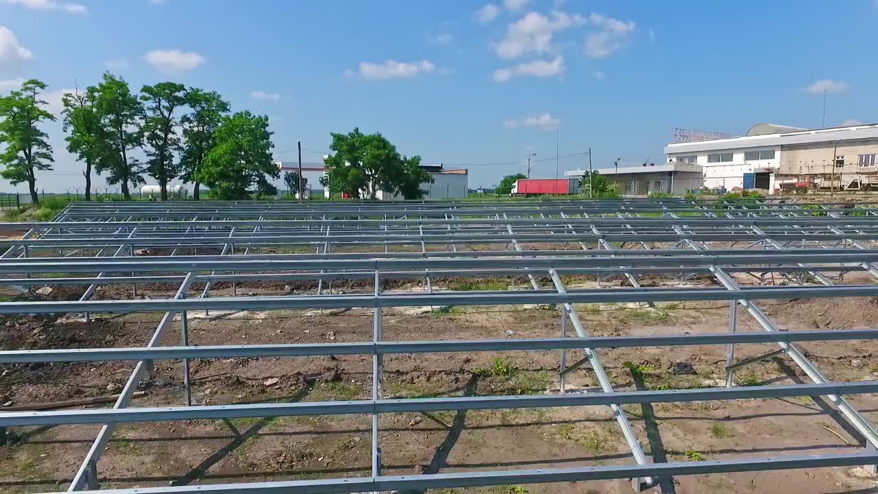 Building of innovative solar power station in nature. Metal basis for future solar panels on the field. Motion camera back.