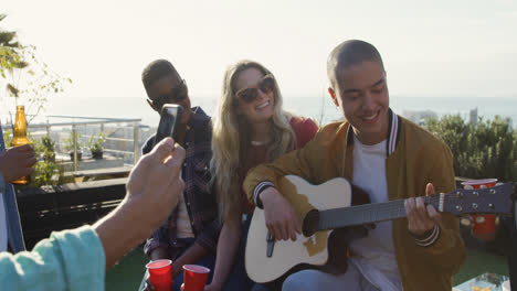 Un-Joven-Tocando-La-Guitarra-En-Una-Azotea-Con-Sus-Amigos.